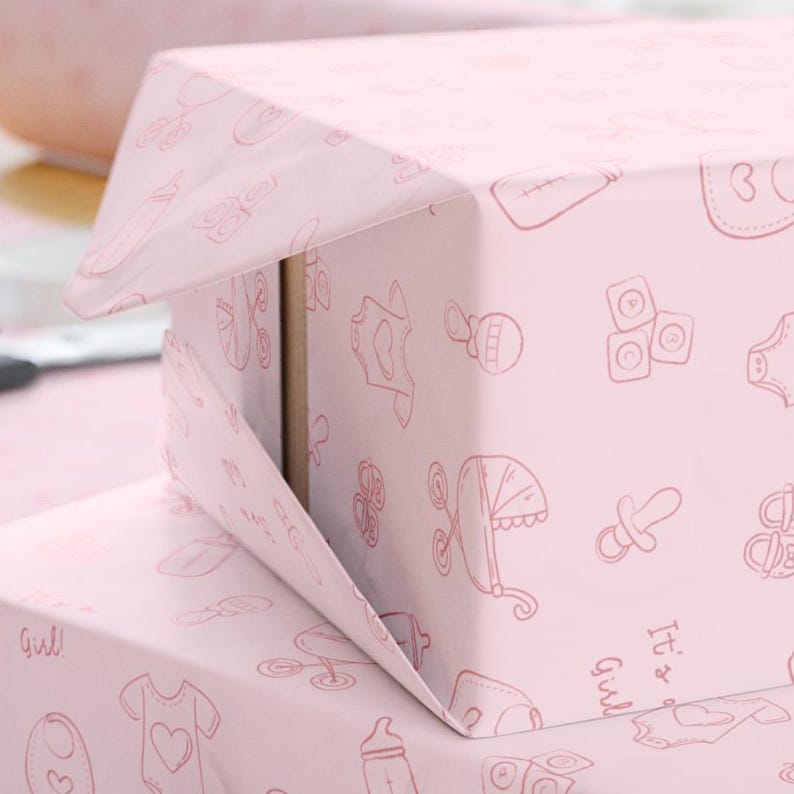 K&ouml;nnte beinhalten: Rosa Geschenkbox, verpackt in Papier mit einem sich wiederholenden Muster von Baby-Illustrationen in einem helleren Rosa. Die Illustrationen umfassen eine Babyflasche, einen Strampler, einen Schnuller und einen Kinderwagen. Die Worte "It's a Girl" sind sichtbar.