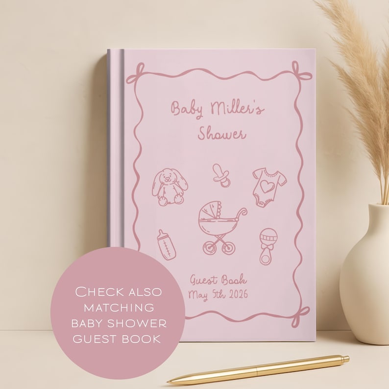 K&ouml;nnte beinhalten: Ein rosa G&auml;stebuch f&uuml;r eine Babyparty mit dem Text "Baby Miller's Shower" und Illustrationen von Babyartikeln. Das Buch enth&auml;lt das Datum "5. Mai 2026" und den Text "Guest Book". Ein goldener Stift liegt auf dem Tisch.