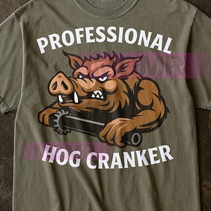 以下が含まれることがあります： オリーブグリーンのTシャツ。白文字で「PROFESSIONAL HOG CRANKER」と書かれています。 怒った茶色のイノシシが歯車を持っている漫画のイラストが描かれています。