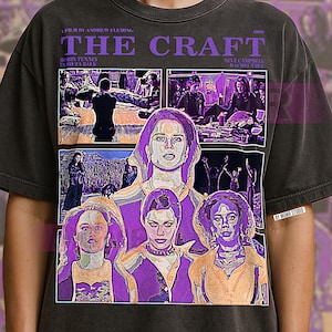 May include: Dark grey t-shirt with a graphic from the film "The Craft." The design features the film's title, cast names, and images of the characters in purple and white. The shirt has a vintage, worn appearance.