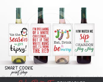 May include: Four wine bottles with decorative tags. The tags feature festive phrases like "'tis the season to get tipsy!" and "Eat, Drink & be merry." The tags have a penguin, Christmas stockings, and other holiday-themed designs. The bottom of the image says "Wine Bottle Tags PRINTABLES."