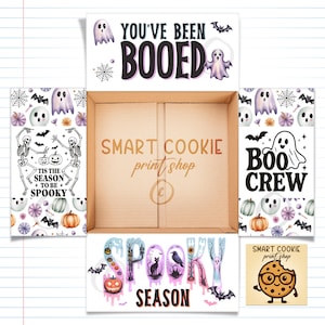 May include: A cardboard box with Halloween-themed decorations. The box is surrounded by white panels with ghosts, pumpkins, bats, and the phrases "You've Been Booed", "Boo Crew", and "Spooky Season". The box also has the text "Smart Cookie print shop".