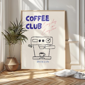 Könnte beinhalten: Ein gerahmtes Poster mit den Worten "COFFEE CLUB" in Blau und "Every day Every Time" in Rosa. Darunter eine Schwarz-Weiß-Illustration einer Kaffeemaschine mit einer Tasse. Die Worte "Daily Life" sind darunter geschrieben.