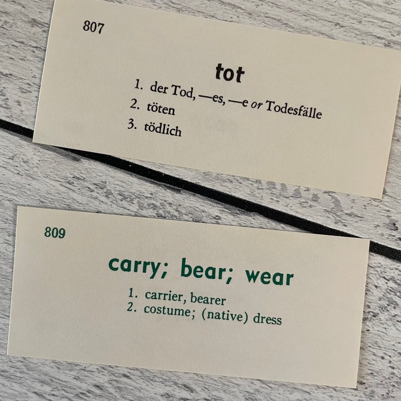 May include: Two vintage flashcards with German and English vocabulary words. The top card reads "tot" with German translations. The bottom card reads "carry; bear; wear" with English translations. The cards are cream-colored with black and green text.
