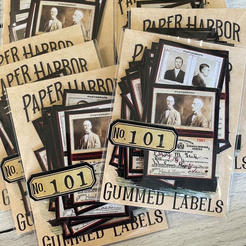 Op de afbeelding: Vintage gummi labels en foto's. De afbeeldingen tonen sepia-getinte portretten en documenten, met de tekst "PAPER HARBOR", "PHOTOGRAPH" en "GUMMED LABELS". Elk label is gemarkeerd met "No. 101".