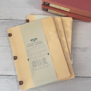 May include: A stack of vintage index sheets with copper reinforced edges and a clear plastic divider. The sheets are a light tan color and feature text that reads "EVERYTHING UNDER CONTROL" and "NATIONAL BLANK BOOK COMPANY HOLYOKE, MASSACHUSETTS".