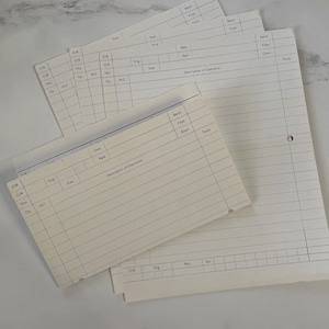 May include: A collection of vintage, lined paper sheets and cards, likely for record-keeping or documentation. The papers are off-white with printed sections for data entry, including fields for job, operation, and description. Some sheets have pre-punched holes.