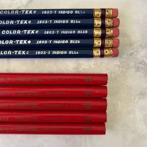 May include: A collection of pencils, some indigo blue and some red. The blue pencils have gold-colored metal bands, purple bands, and pink erasers. The text "COLOR-TEX" and "1803-T INDIGO BLUE" are printed on the blue pencils.