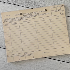 May include: A vintage South Buffalo Railway Company switching order form. The beige paper form features printed lines and text, including "Switching Order" and fields for car information, commodity details, and time stamps. Two holes are punched at the top.
