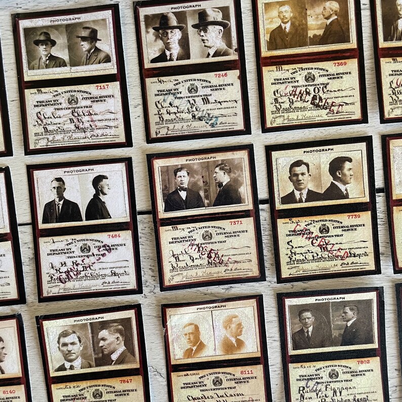 Op de afbeelding: Een verzameling vintage kaarten met sepiafoto's van mannen in pakken en hoeden. Elke kaart bevat tekst, handtekeningen en nummers, met een donkere rand en een cr&egrave;mekleurige achtergrond. De kaarten zijn gerangschikt op een licht oppervlak.