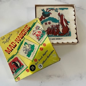 Op de afbeelding: Vintage "Mad-Nagerie" snackservettenbox met illustraties van cartoon dieren. De gele doos heeft groene en rode accenten. Een doos met servetten met een geschulpte rand toont een cartoon stinkdier en konijnen met de tekst "I HATE SPRING!"