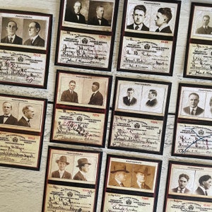 Op de afbeelding: Een verzameling vintage kaarten met sepia-foto's van mannen. Elke kaart bevat het woord "PHOTOGRAPH" en tekst van het Treasury Department, Internal Revenue Service. De kaarten zijn omlijst met een donker bordeauxrode rand.