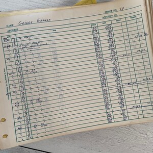 May include: An open ledger book with ruled lines and handwritten entries. The top of the page reads "GRIGGS GARAGE" and "SHEET NO. 13". The entries include dates, items, and financial figures, with a yellow tab visible.