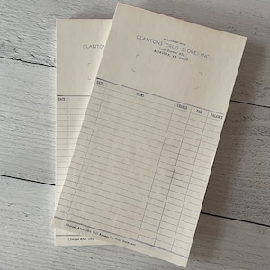 May include: Two vintage Clantons Drug Store, Inc. invoice pads. Each pad features a lined layout for items, charges, payments, and balance. The top of each pad includes the store's name and address in Altavista, VA.