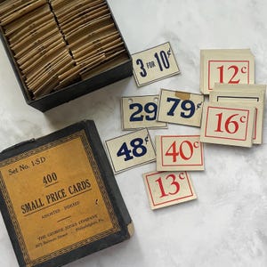 May include: Vintage small price cards with various prices in red and blue, including "3 for 10¢". The cards are from "The George Jones Company" and are assorted and indexed. A box contains many price cards.