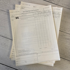 May include: A stack of vintage Soo Line Railroad Company expense report forms. The forms are printed on aged, off-white paper with black ink. The forms have multiple columns for recording expenses, with the company name and form number visible.