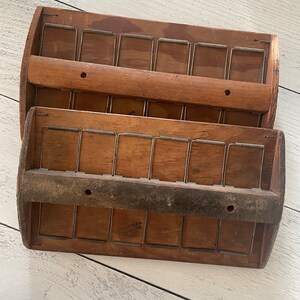 Puede incluir: Dos clasificadores de correo de madera vintage, cada uno con seis compartimentos. Los clasificadores están hechos de madera marrón claro y cuentan con divisores de alambre de metal. La madera muestra una veta natural y signos de desgaste, lo que indica la edad. El diseño es simple y funcional.