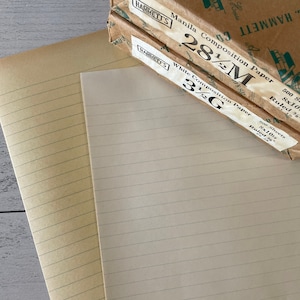 Può includere: Carta e quaderni di composizione vintage. L'immagine mostra due fogli aperti di carta a righe color crema e beige, con una pila di rotoli di carta con l'etichetta "HAMMETT'S Manila Composition Paper" e "White Composition Paper". La carta misura 20,3 x 25,4 cm.