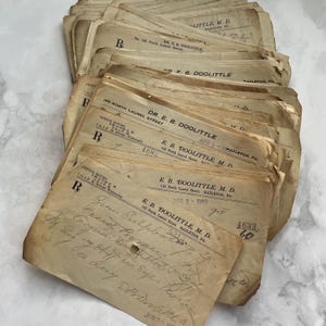 Puede incluir: Una pila de formularios médicos antiguos de color beige. Los formularios son de E. B. Doolittle, M.D., con notas manuscritas y la dirección 145 North Laurel Street, Hazleton, PA. Los formularios tienen la letra "R" y datan de 1909.