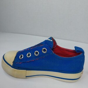 Op de afbeelding: Blauwe canvas instapper met een cr&egrave;mekleurige neus en zool. De schoen heeft metalen vetergaten en een rode binnenvoering. De zool heeft een blauwe streep. Een casual schoen voor dagelijks gebruik.