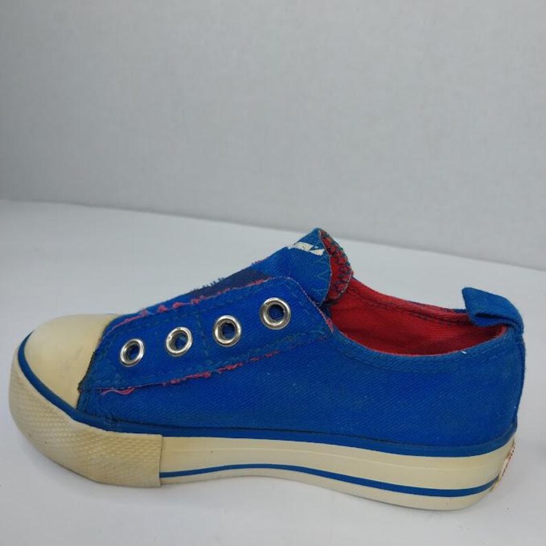 Op de afbeelding: Blauwe canvas instapper met een cr&egrave;mekleurige neus en zool. De schoen heeft metalen vetergaten en een rode binnenvoering. De zool heeft een blauwe streep. Een casual schoen voor dagelijks gebruik.