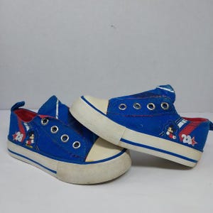 Op de afbeelding: Een witte keramische mok met een zwart handvat en de tekst "But First, Coffee" in een vetgedrukte, zwarte letter. De mok staat tegen een vage achtergrond, wat een gezellige setting suggereert.