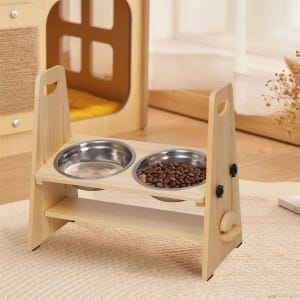 May include: A light-colored wooden pet feeder with two stainless steel bowls. One bowl is filled with dry pet food. The feeder has a handle on each side and a lower shelf for storage. The feeder is 12 inches wide.
