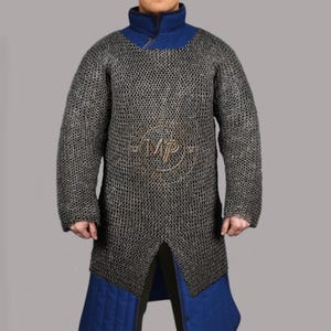 May include: A chainmail shirt with a blue collar and blue accents. The shirt is made of small, interlocking metal rings. The shirt has long sleeves and a split front. The shirt is part of a medieval or historical costume.
