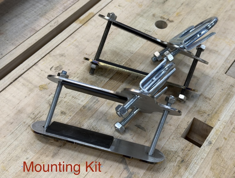 Puede incluir: Un kit de montaje met&aacute;lico con soportes plateados, pernos y almohadillas de goma negra. El kit incluye m&uacute;ltiples piezas, ensambladas con tuercas y pernos, y est&aacute; dise&ntilde;ado para un montaje seguro. El texto "Mounting Kit" es visible.