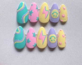 Könnte beinhalten: Ein Set aus zehn künstlichen Nägeln in verschiedenen Designs. Die Nägel weisen eine Mischung aus Farben auf, darunter Türkis, Rosa, Gelb und Lila. Zu den Designs gehören Wirbel, Sterne, Blitze, Smiley-Gesichter und Blumen. Die Nägel sind oval geformt.