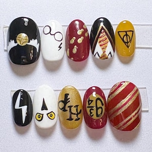 May include: A set of ten press-on nails featuring various designs including a golden snitch, round glasses with a lightning bolt, gold dots on red, a tie pattern, the deathly hallows symbol, a lightning bolt, owl eyes, HP letters, 9 3/4, and stripes.