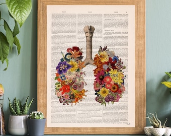 May include: A framed print of a human lung anatomy illustration with colorful flowers arranged to resemble the shape of the lungs. The print is on a white background with black text and is framed in a light brown wood frame.