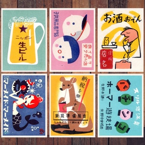 May include: Nine vintage matchbox labels with colorful illustrations. The labels feature a beer bottle, a kangaroo, a mermaid, a man drinking sake, a woman with a baby, and a variety of other designs. The labels are printed in Japanese and English.