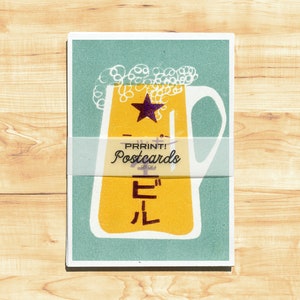 May include: A vintage-style postcard featuring a yellow beer stein with a star and the Japanese word "ビール" (beer) in white. The postcard has a teal background and a white banner that reads "PRRINT! Postcards - SET OF 6".