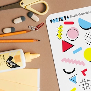 Op de afbeelding: Een vel met kleurrijke geometrische patroonstickers met de tekst "PRINT! Memphis Pattern Stickers" bovenaan. De stickers bevatten een verscheidenheid aan vormen, waaronder zigzag, cirkels, vierkanten, driehoeken en stippen. De stickers zijn op een witte achtergrond.