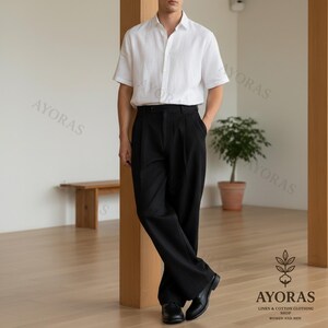 Men’s black pleated wide leg trousers with high waist and relaxed fit, styled with white short sleeve shirt