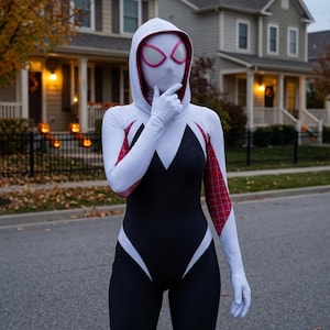 May include: A full-body spandex bodysuit featuring a white hood, white sleeves with a red web pattern, and a black torso section. The mask is white with large, angular eye lenses outlined in pink, covering the entire head and face area.