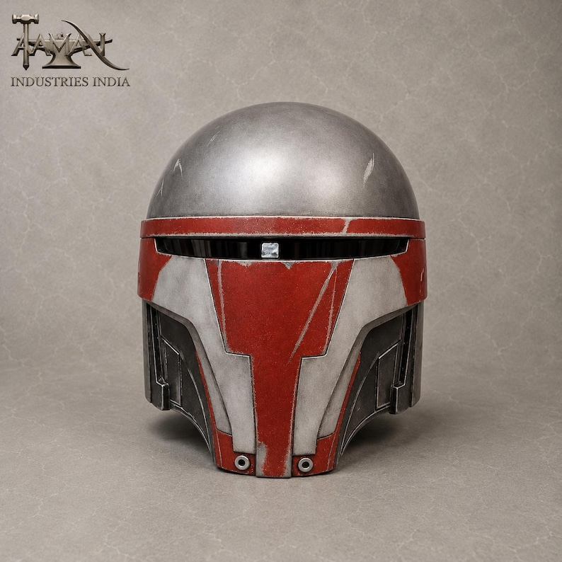 May include: A silver and red helmet with a weathered appearance. The helmet features a rounded top and a faceplate with red and white accents. The text "INDUSTRIES INDIA" is visible in the upper left corner.