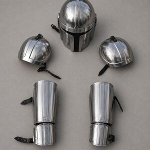 May include: A set of polished metal armor pieces, including a helmet, two shoulder pieces, and two arm guards. The helmet has a distinctive T-shaped visor. The arm guards and shoulder pieces have leather straps. The logo "INDUSTRIES INDIA" is visible in the top left corner.