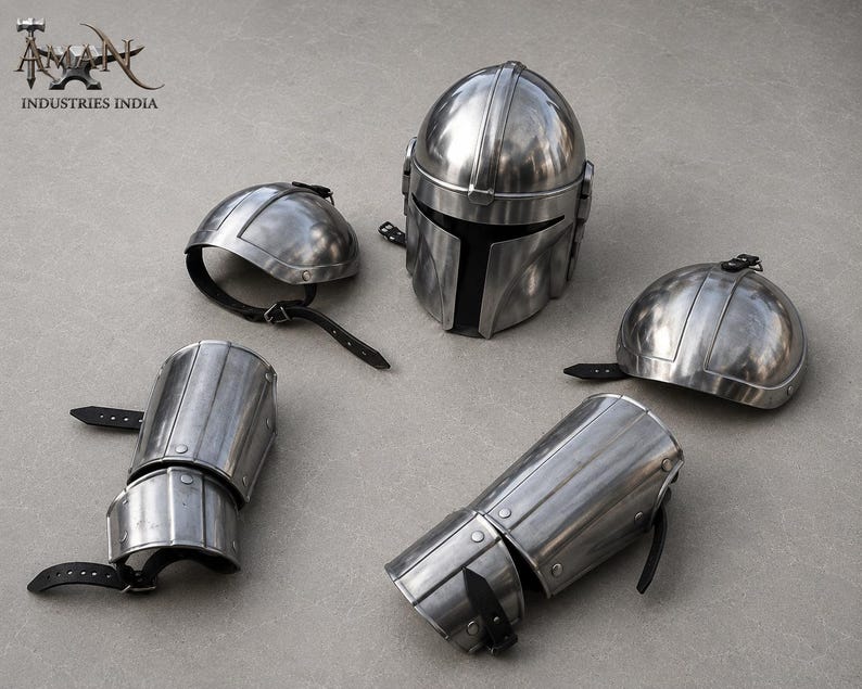 May include: A set of polished metal armor pieces, including a helmet, two shoulder guards, and two arm guards. The helmet has a distinctive T-shaped visor. The armor is silver in color and features black leather straps.