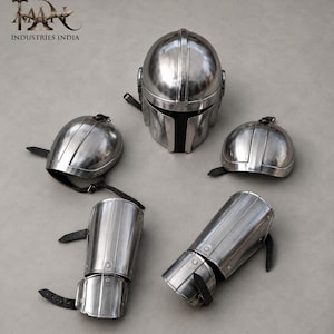 May include: A set of polished metal armor pieces, including a helmet, two shoulder guards, and two arm guards. The helmet has a black visor. The armor is secured with black leather straps. The logo "TAAN INDUSTRIES INDIA" is in the upper left corner.