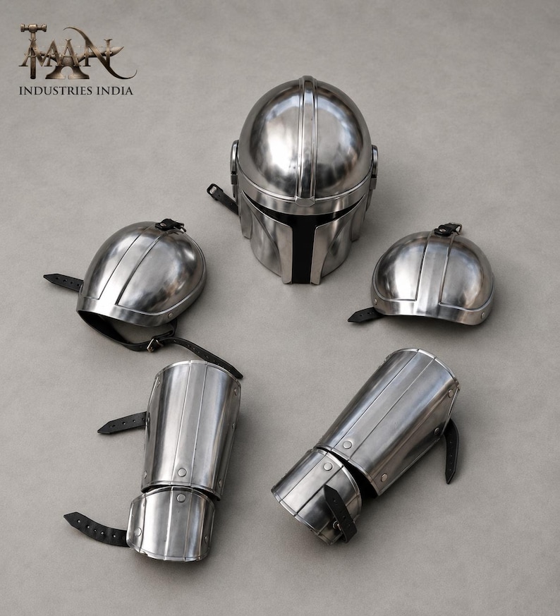 May include: A set of polished metal armor pieces, including a helmet, two shoulder guards, and two arm guards. The helmet has a black visor. The armor is secured with black leather straps. The logo "TAAN INDUSTRIES INDIA" is in the upper left corner.