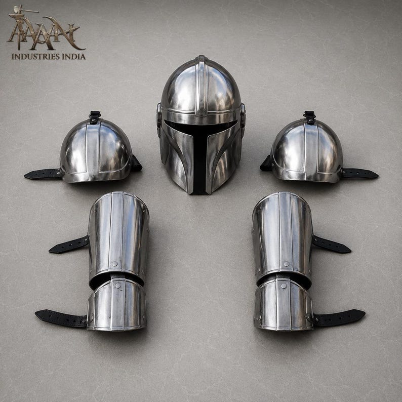 May include: A set of metallic silver Mandalorian armor pieces, including a helmet, two shoulder caps, and two arm guards. The helmet has a T-shaped visor. The arm guards and shoulder caps have black straps. The armor is displayed on a gray surface.