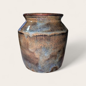 May include: A ceramic vase with a wide, rounded body and a short, flared neck. The surface features a mottled glaze with blended tones of deep brown, earthy tan, and subtle hints of cool blue, creating a textured, multi-layered appearance.