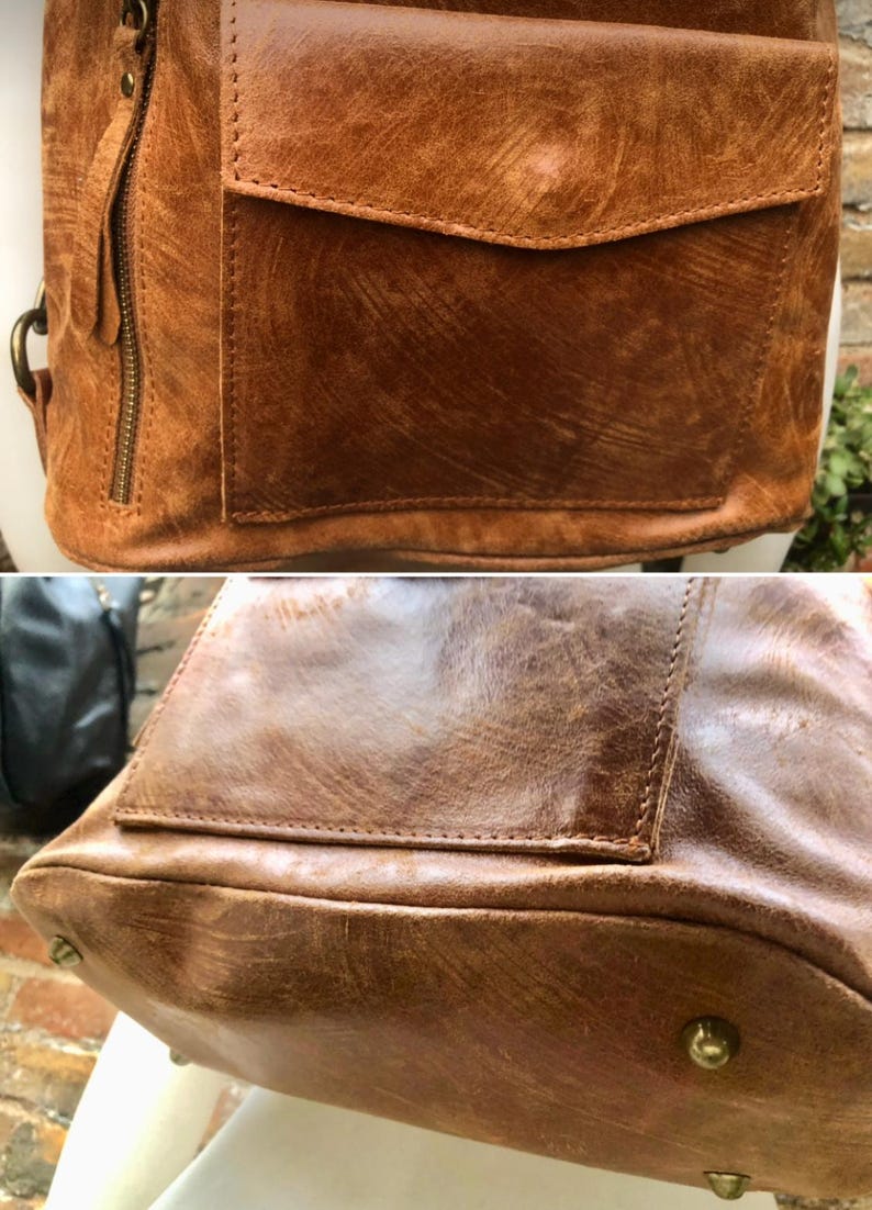 Op de afbeelding: Een bruine leren rugzak met een groot voorvak en een ritssluiting. De rugzak heeft een verweerde look en is gemaakt van hoogwaardig leer.