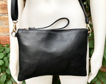 Könnte beinhalten: Eine schwarze Leder-Umhängetasche mit goldfarbenem Reißverschluss und Beschlägen. Die Tasche hat eine strukturierte Oberfläche und einen langen, verstellbaren Riemen.