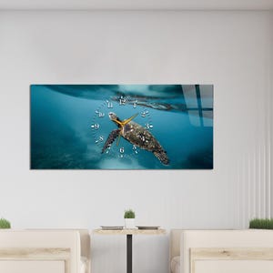 May include: A rectangular wall clock featuring a sea turtle swimming underwater. The clock face is superimposed over the image, with a blue background and gold-colored hands. The clock's numbers are in a simple, easy-to-read font.
