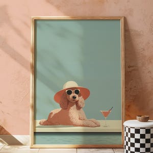 May include: A framed art print depicting a poodle wearing sunglasses and a sun hat, relaxing by a pool with a cocktail. The artwork has a retro, summery feel with a light blue and peach colour palette.