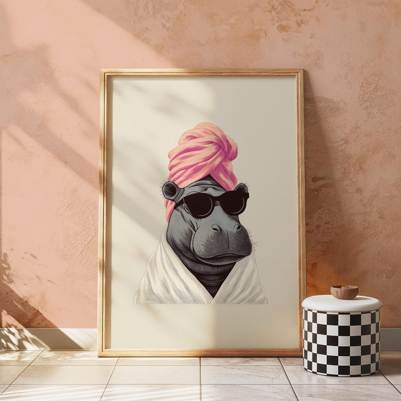 May include: A framed art print featuring a hippo wearing sunglasses, a pink turban, and a white robe. The hippo is depicted in a relaxed pose, with a neutral background. A black and white checkered stool with a wooden top is in the foreground.