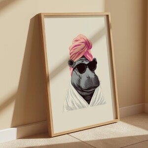 May include: A framed art print featuring a stylized hippo wearing sunglasses, a pink turban, and a white robe. The hippo is depicted in a relaxed pose, suggesting a spa or relaxation theme. The artwork is set against a neutral background.